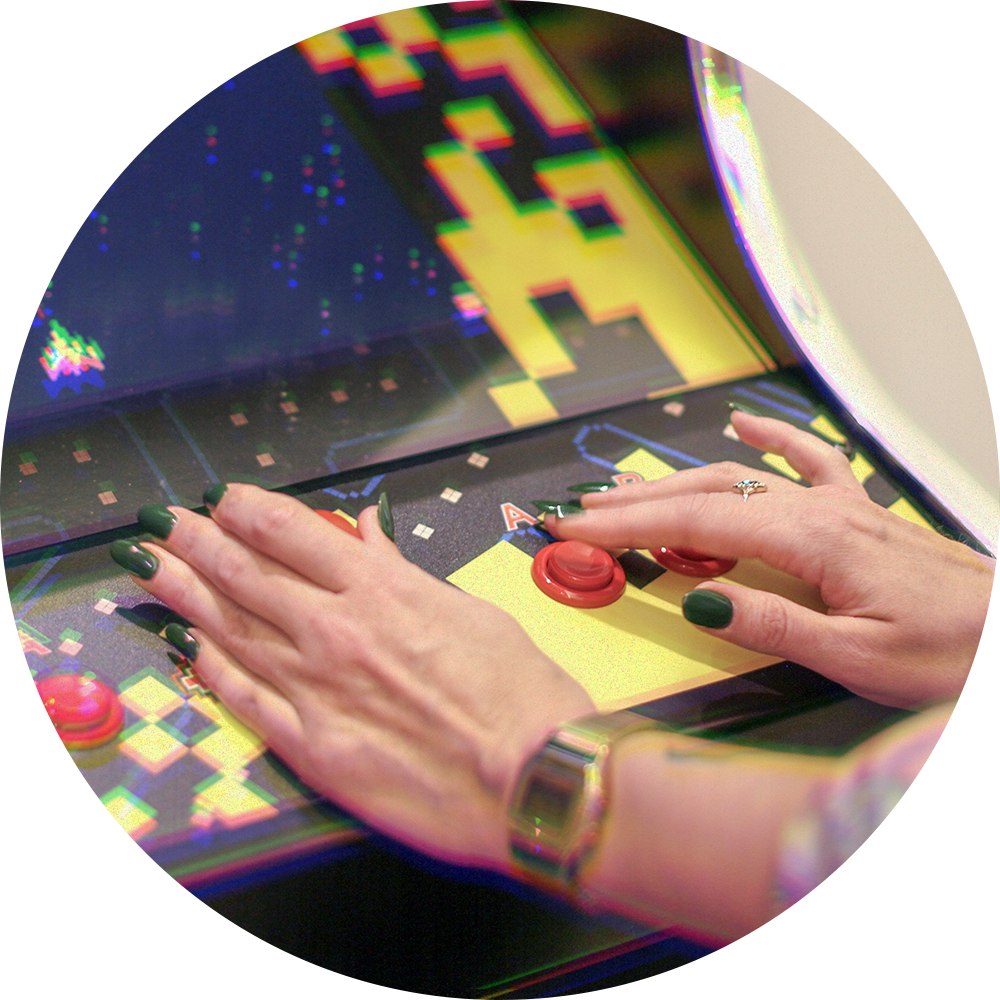 Gros plan sur les mains d’une femme qui appuie sur les boutons d’un arcade rétro PACMAN dans les bureaux de Reflector à Montréal.